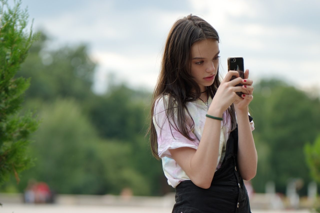 Adolescentă singură cu telefonul în aer liber Adolescentă singură cu telefonul în aer liber